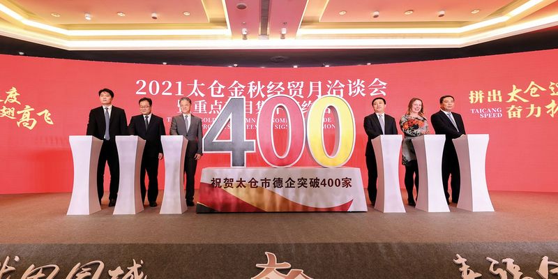 Mitarbeiter stehen auf einer Bühne in China, Hintergrund rotes Tuch über die ganze Bühne gespannt, davor vier Mitarbeiter von Häring