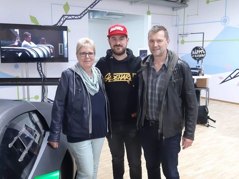 drei Personen neben einem Auto, lächeln in die Kamera