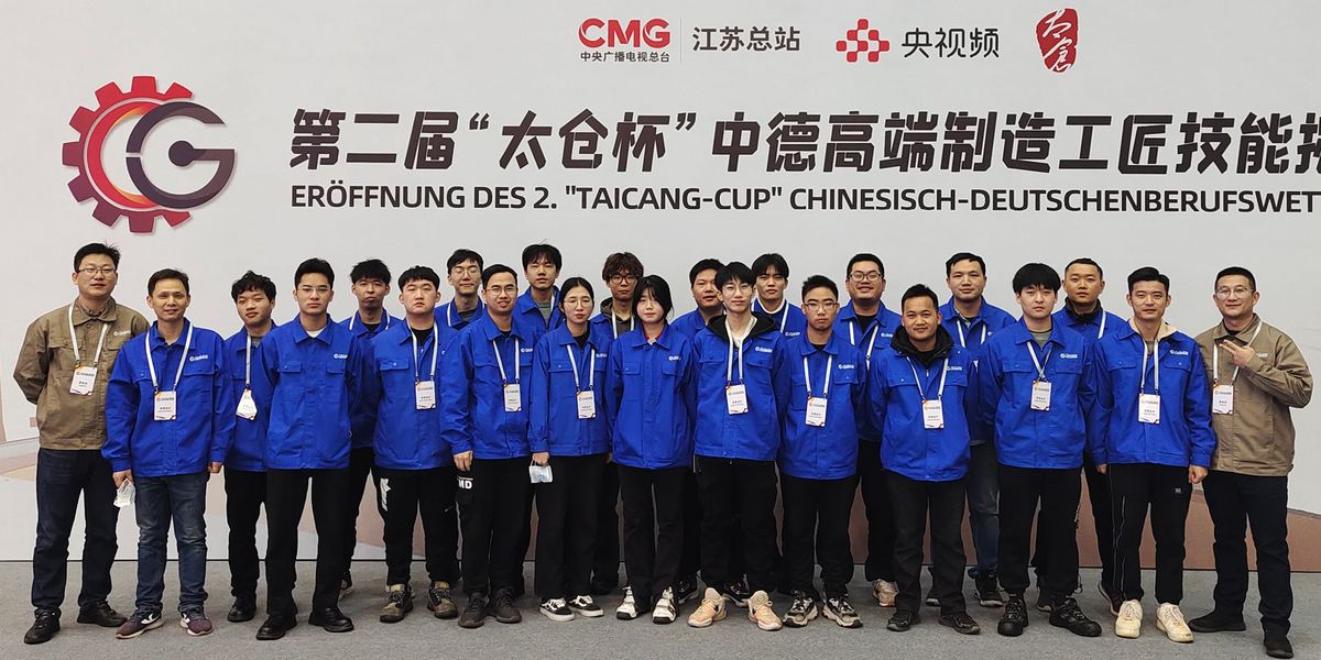Gruppenfoto Taicang Mitarbeiter blaue Jacke Hintergrund Wand mit schwarzer Schrift "Eröffnung des 2. "Taicang cup" Chinesisch Deutschenberufswet"